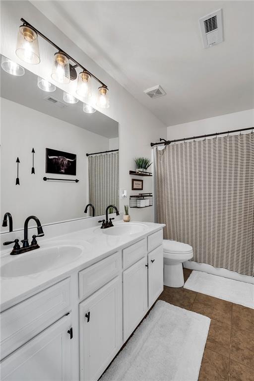 bathroom with tile patterned floors, curtained shower, vanity, and toilet