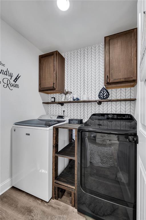 laundry area with cabinets, wood-type flooring, and washer and dryer