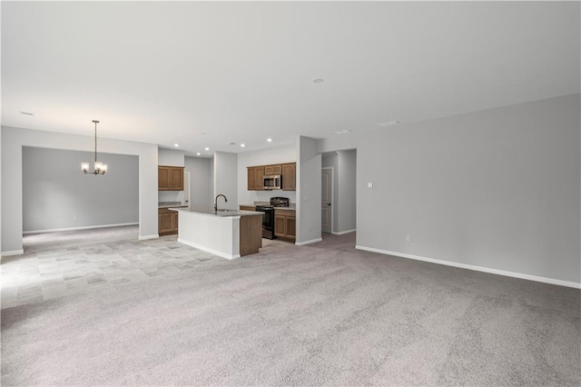 kitchen featuring an inviting chandelier, stainless steel microwave, open floor plan, black gas range, and an island with sink