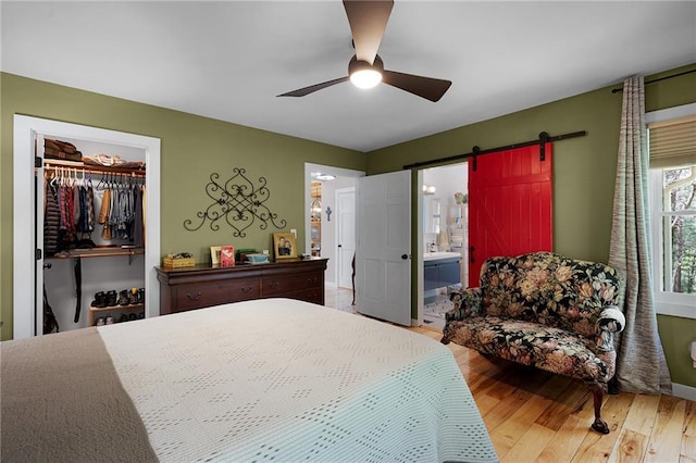 306 Pig Trl, Cherry Log, GA 30522 - bedroom featuring wood finished floors, a barn door, a spacious closet, a ceiling fan, and ensuite bath