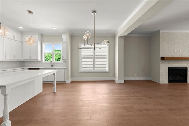 1417 Coretta Scott Bnd, Atlanta, GA 30318 - kitchen featuring light countertops, crown molding, white cabinets, light wood-type flooring, and hanging light fixtures