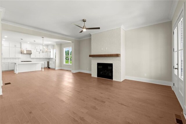 1417 Coretta Scott Bnd, Atlanta, GA 30318 - unfurnished living room featuring a ceiling fan, crown molding, light wood-style flooring, a fireplace, and baseboards