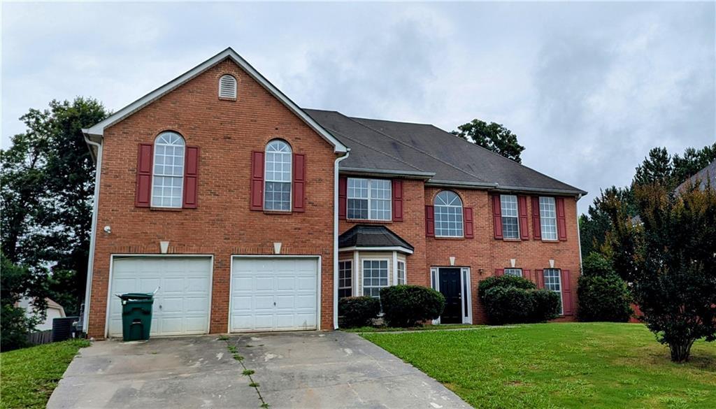 4373 Abram Dr, Conley, GA 30288 - colonial inspired home featuring brick siding, concrete driveway, a front yard, and cooling unit