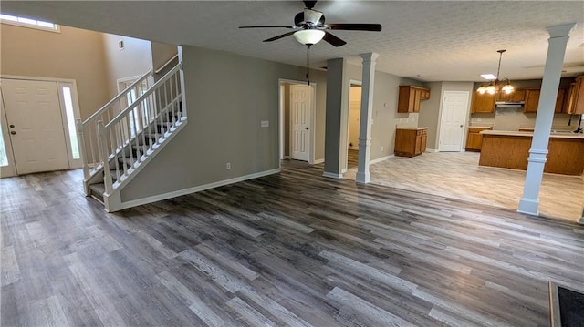 4373 Abram Dr, Conley, GA 30288 - unfurnished living room with decorative columns, dark wood-type flooring, ceiling fan, baseboards, and stairway