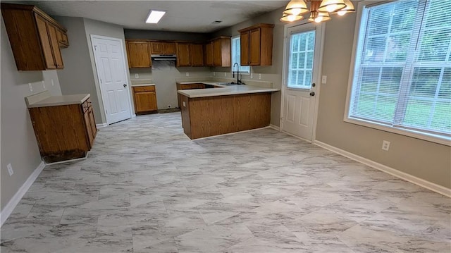 4373 Abram Dr, Conley, GA 30288 - kitchen with a peninsula, brown cabinets, a sink, extractor fan, and baseboards