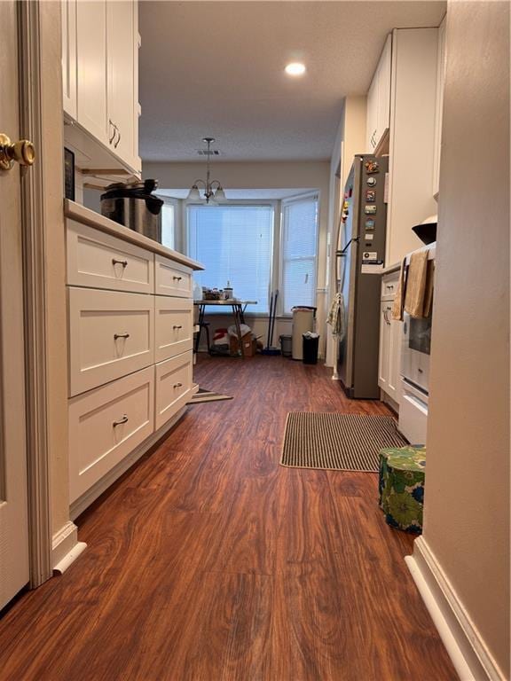 kitchen with decorative light fixtures, a notable chandelier, dark hardwood / wood-style floors, white cabinets, and stainless steel fridge