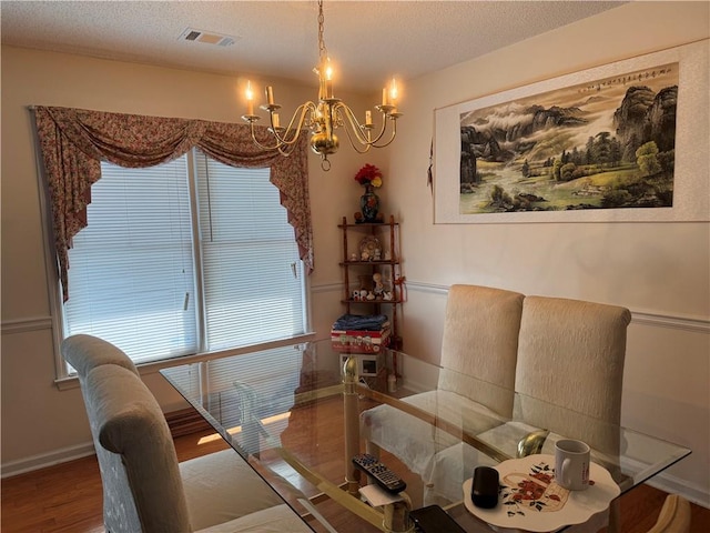 dining room with a textured ceiling, hardwood / wood-style floors, and a notable chandelier