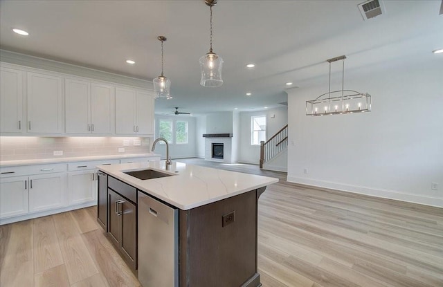 kitchen featuring dishwasher, backsplash, open floor plan, a fireplace, and a sink