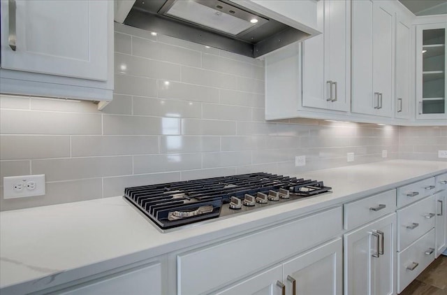 kitchen featuring stainless steel gas stovetop, light countertops, white cabinetry, and custom range hood