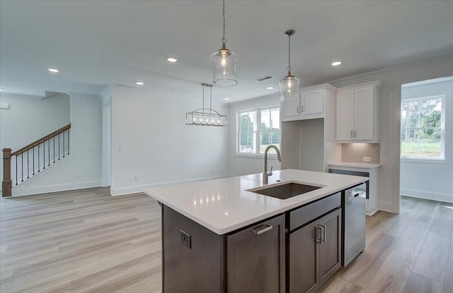 kitchen featuring light countertops, dishwasher, light wood finished floors, and a sink