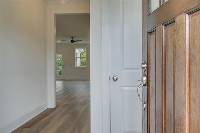 hall featuring dark wood-type flooring and baseboards