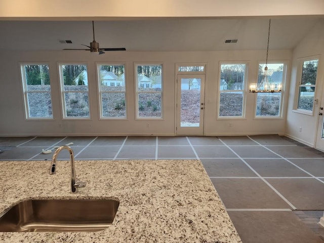 sunroom with ceiling fan with notable chandelier, lofted ceiling, and sink