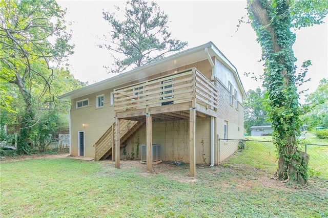 rear view of property with cooling unit, a deck, and a lawn