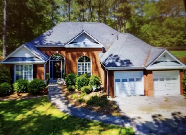 view of front of house with a garage, a front yard, brick siding, and driveway