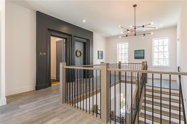 hallway with a notable chandelier, an upstairs landing, wood finished floors, baseboards, and recessed lighting