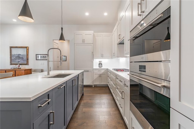 kitchen with appliances with stainless steel finishes, gray cabinets, light countertops, and a sink