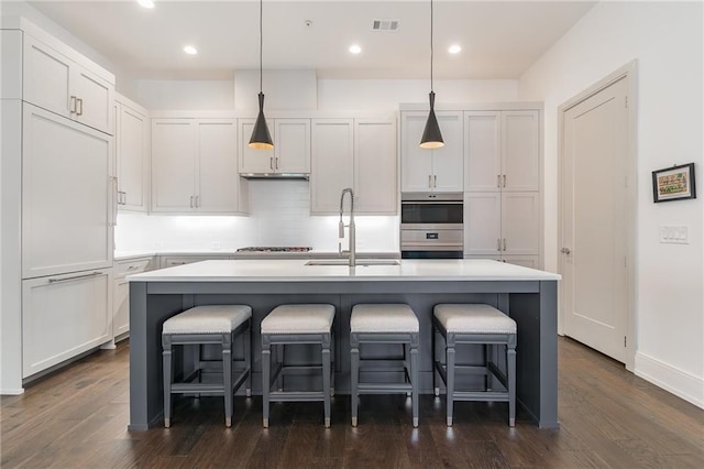 kitchen with dark wood-style floors, light countertops, a sink, and a breakfast bar area