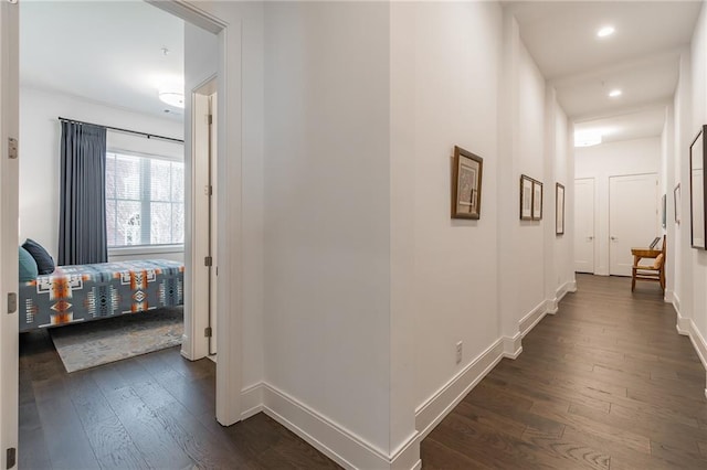 hallway with dark wood-type flooring, baseboards, and recessed lighting