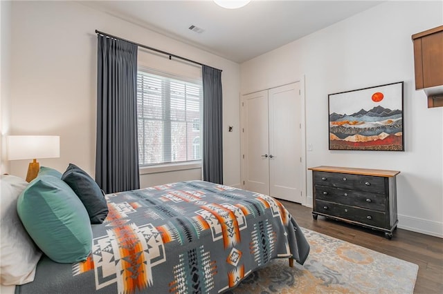 bedroom with baseboards, visible vents, a closet, and wood finished floors