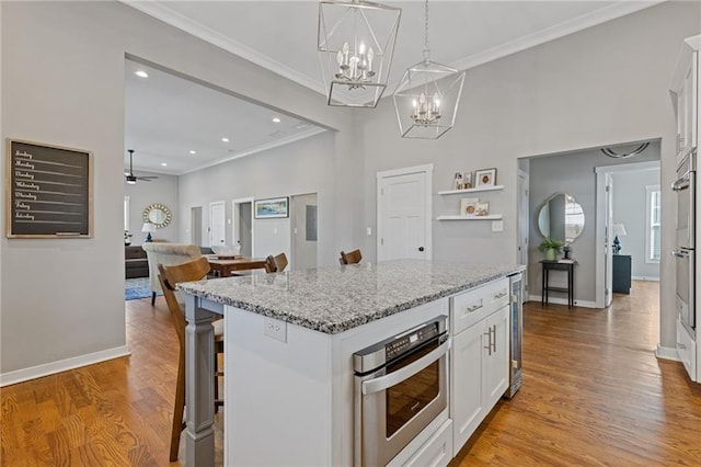 459 James P Brawley Dr NW, Atlanta, GA 30318 - kitchen featuring white cabinetry, a breakfast bar area, stainless steel oven, light wood-type flooring, and ornamental molding
