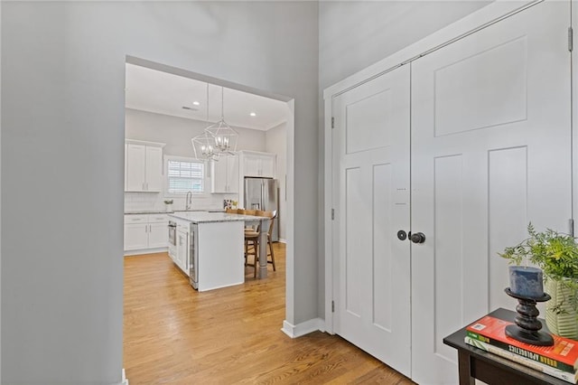 459 James P Brawley Dr NW, Atlanta, GA 30318 - interior space featuring light wood finished floors, a breakfast bar, stainless steel refrigerator with ice dispenser, white cabinets, and an inviting chandelier