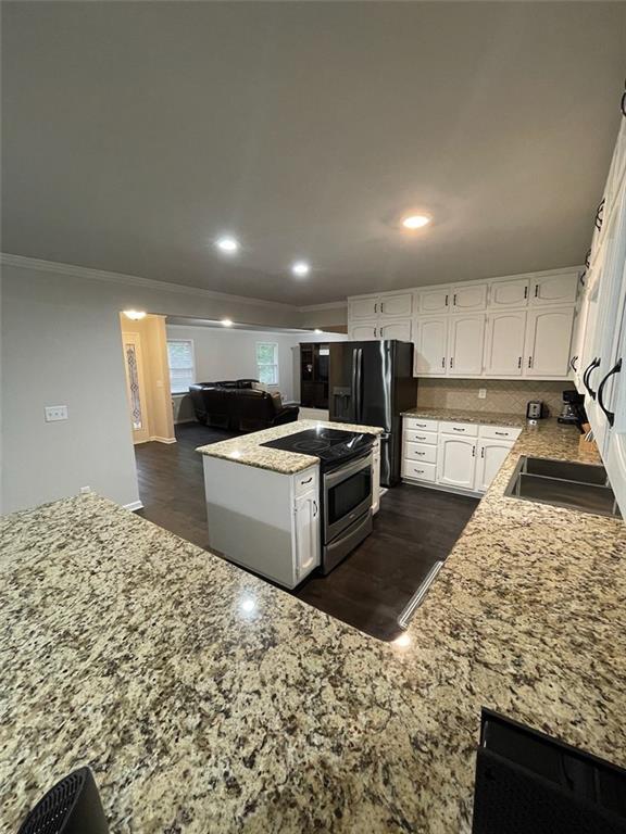 2166 Lake Ridge Ter, Lawrenceville, GA 30043 - kitchen with crown molding, stainless steel electric range, white cabinets, light stone counters, and black refrigerator with ice dispenser