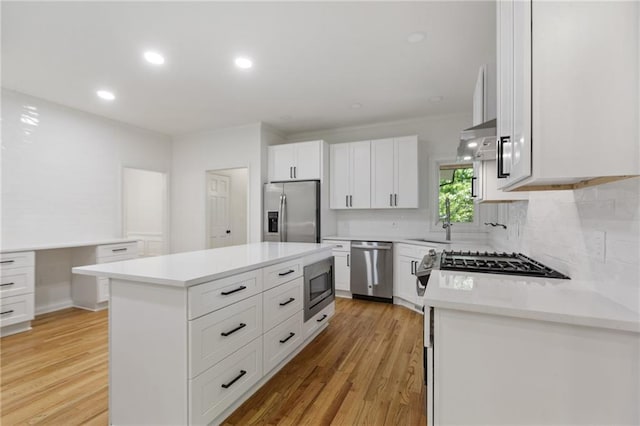 kitchen with a center island, stainless steel appliances, white cabinetry, and light hardwood / wood-style floors