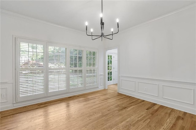 unfurnished dining area with a chandelier, crown molding, and light hardwood / wood-style floors