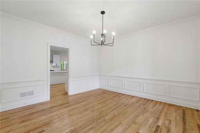 unfurnished dining area with a chandelier, light hardwood / wood-style flooring, and ornamental molding