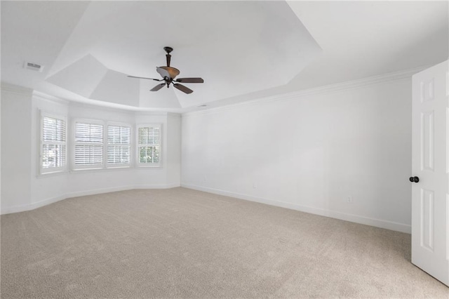 carpeted empty room with a raised ceiling, ceiling fan, and ornamental molding