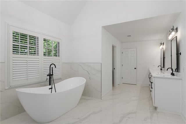 bathroom featuring vanity, vaulted ceiling, tile walls, and a tub