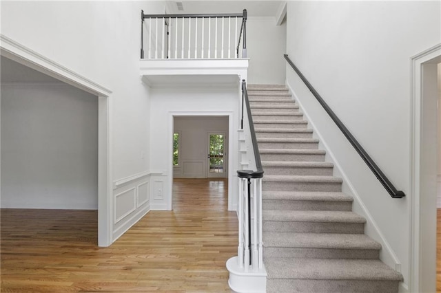 staircase with hardwood / wood-style flooring and crown molding