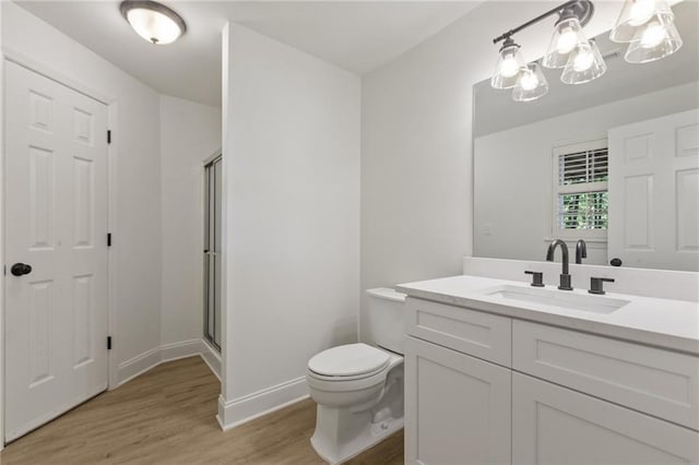 bathroom featuring hardwood / wood-style floors, vanity, toilet, and an enclosed shower