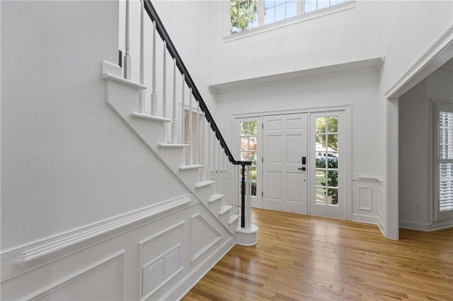 foyer with a towering ceiling and light wood-type flooring