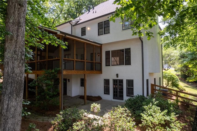 rear view of property featuring a sunroom, a patio, and french doors