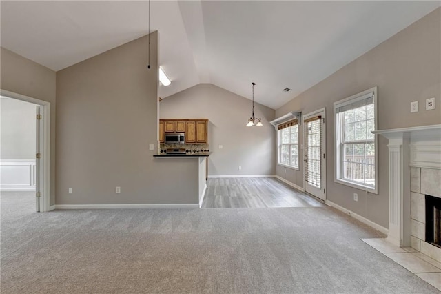 unfurnished living room featuring a fireplace, light colored carpet, and vaulted ceiling