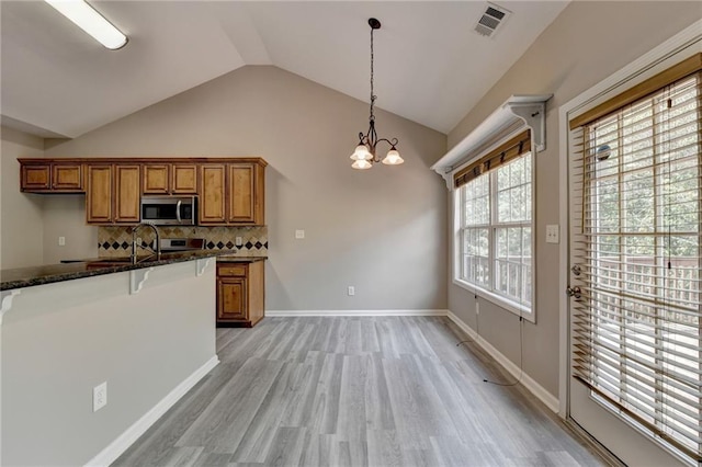 kitchen with light hardwood / wood-style flooring, vaulted ceiling, tasteful backsplash, decorative light fixtures, and a chandelier