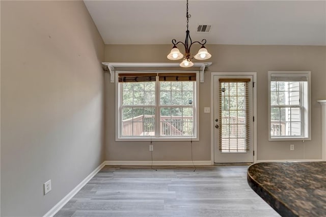 doorway to outside with a chandelier, a wealth of natural light, and wood-type flooring