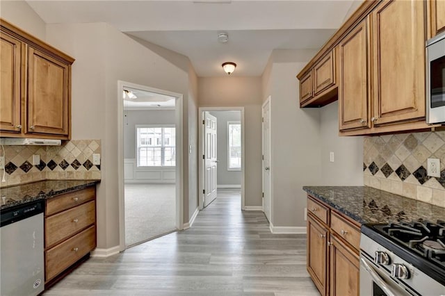 kitchen with stainless steel appliances, tasteful backsplash, and dark stone counters