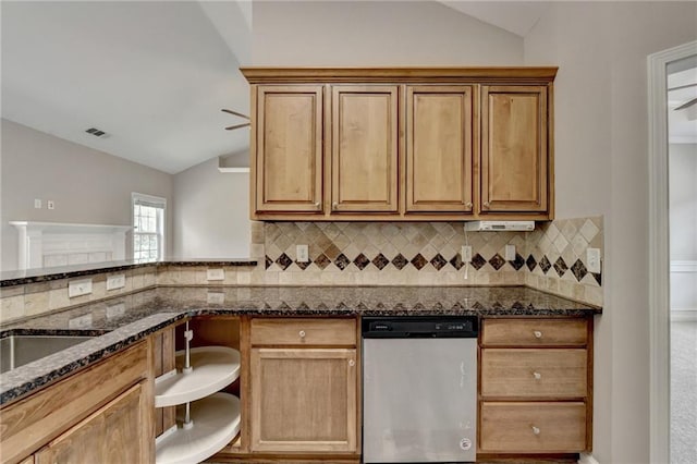 kitchen with vaulted ceiling, tasteful backsplash, stainless steel dishwasher, and dark stone counters