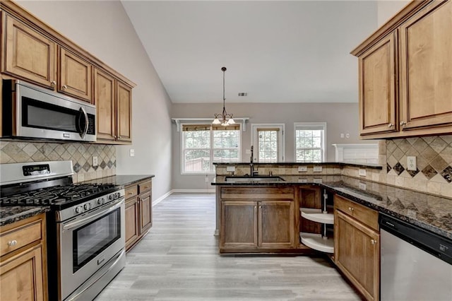 kitchen with lofted ceiling, backsplash, dark stone counters, sink, and appliances with stainless steel finishes