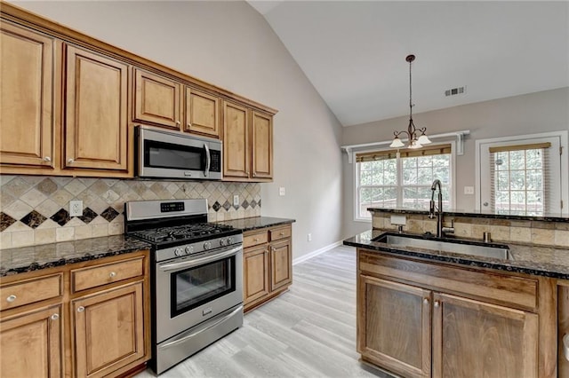 kitchen with sink, light hardwood / wood-style flooring, vaulted ceiling, stainless steel appliances, and a chandelier