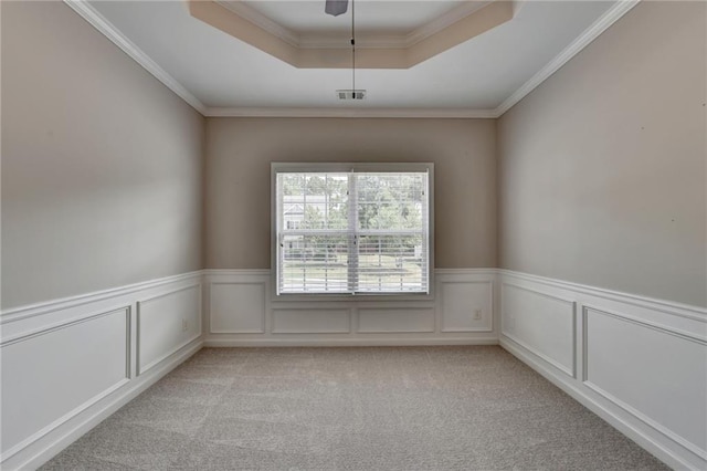 spare room featuring light colored carpet, a tray ceiling, and crown molding