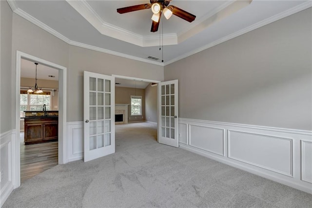 carpeted empty room with french doors, ceiling fan with notable chandelier, and ornamental molding