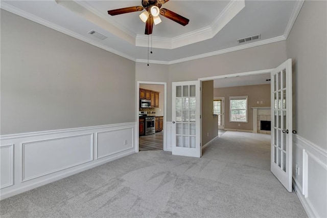 unfurnished room featuring french doors, light colored carpet, and ornamental molding