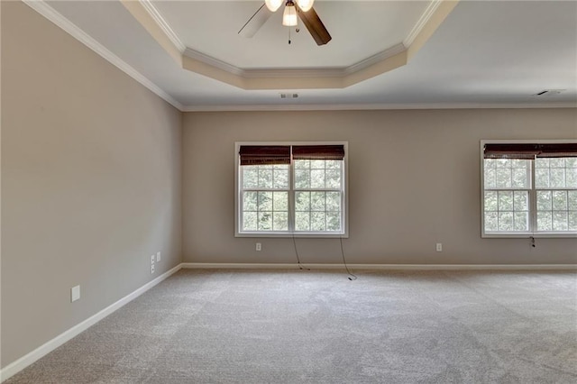 carpeted empty room with a raised ceiling, ceiling fan, and crown molding