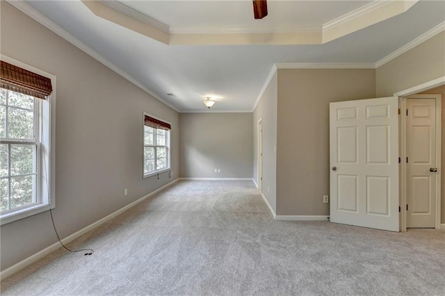 empty room featuring light carpet, a raised ceiling, ceiling fan, and crown molding