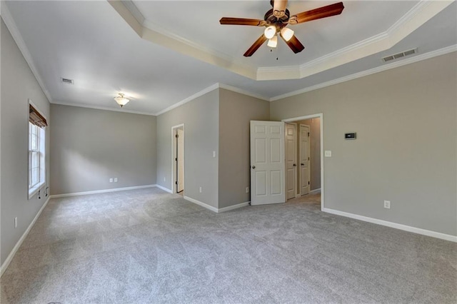 empty room featuring a raised ceiling, crown molding, ceiling fan, and light colored carpet