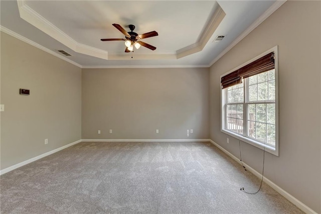 empty room featuring a tray ceiling, ceiling fan, carpet flooring, and ornamental molding