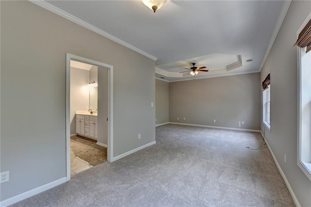 carpeted spare room with a tray ceiling, ceiling fan, and crown molding